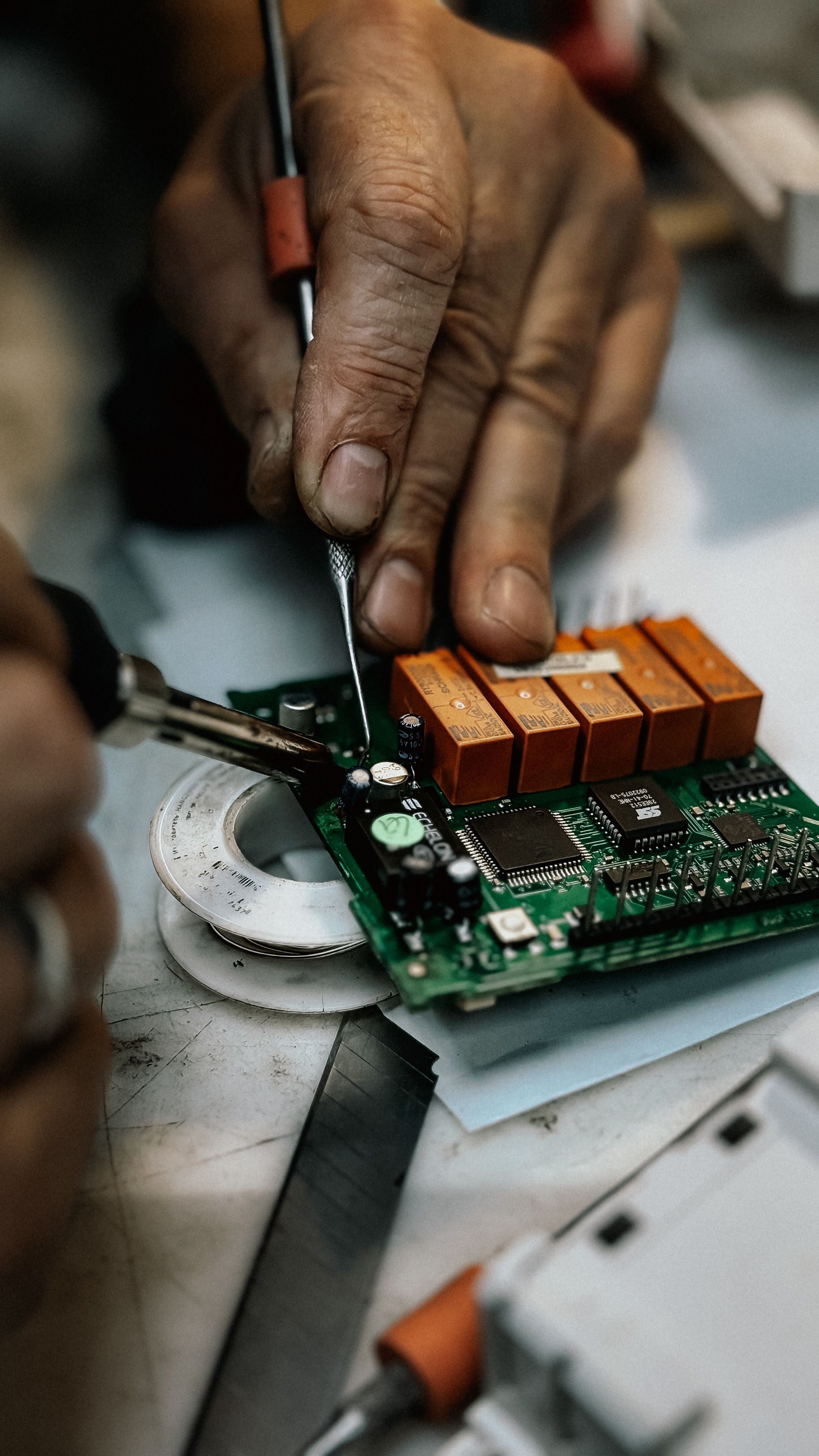 Technician performing component‑level PCB rework on a damaged board